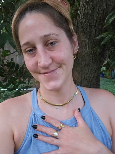 Customer's Sunstar Ring worn on a hand, layered with other gold-toned rings.