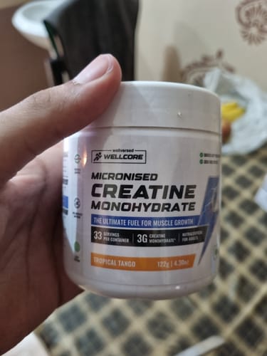 Customer's hand holding a jar of Wellcore Pure Micronised Creatine Monohydrate Tropical Tango.