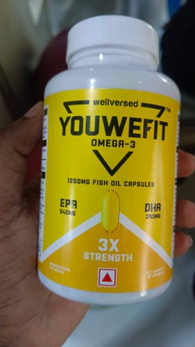 Customer's hand holding a white bottle of YouWeFit Omega-3 Fish Oil, showing the yellow label and product details.