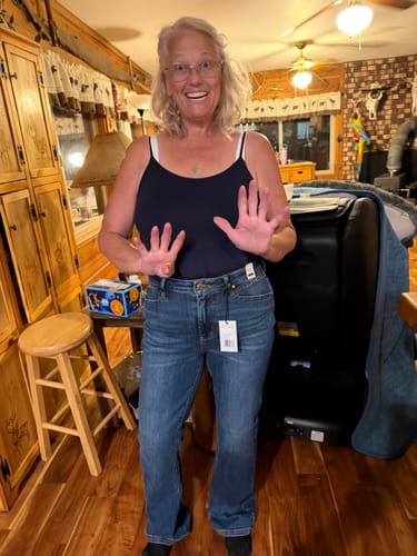 Customer's Judy Blue bootcut jeans in blue denim, showing front fit with tags attached while standing at home.
