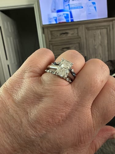 Customer's hand wearing the radiant cut DovEggs lab grown diamond ring alongside two other bands
