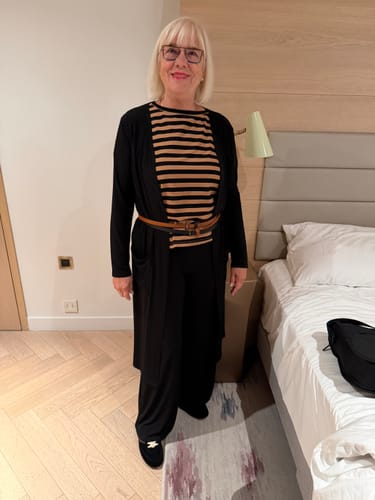 Customer's Brigitte Brianna Essential Set including a striped tank, black cardigan, and black pants in a hotel room.