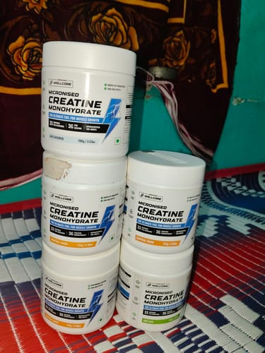 Customer's stack of five Wellcore Micronised Creatine Monohydrate tubs on a patterned surface