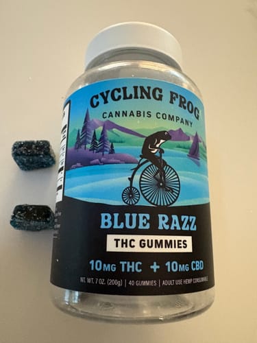 Customer's Blue Razz Gummies jar with two dark blue, rectangular gummies placed next to it.