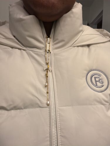 Reviewer's Jellyfish Lariat Necklace draped over the center zipper of a white puffer jacket.