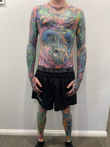 Reviewer showing off their extensive full-body tattoos after using the XL Signature Tattoo Numbing Cream.