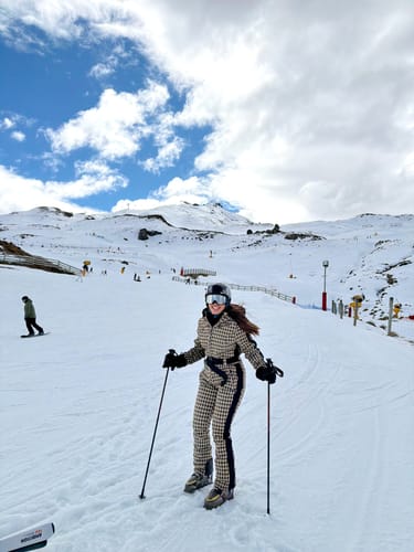 Customer's tan houndstooth ski suit on a person skiing on a snowy mountain