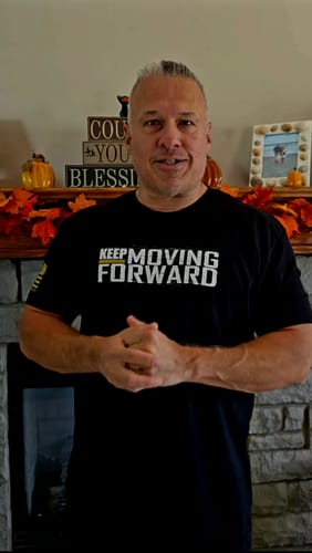 Reviewer wearing a black Keep Moving Forward t-shirt while standing in a room with fall decor