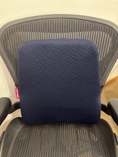 Customer's dark blue textured back support pillow attached to a mesh office chair.