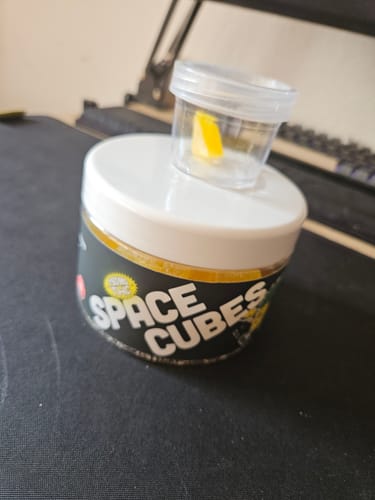 Kunden-Foto der LEAFZ Space Cubes Dose mit einem einzelnen gelben Fruchtgummi im kleinen transparenten Deckel.