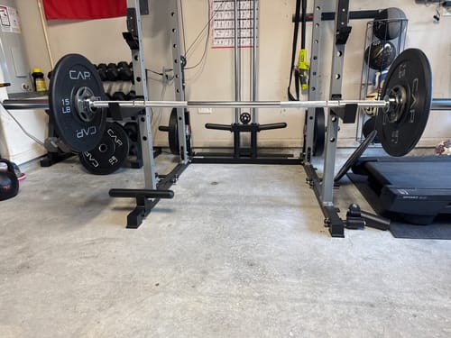 Customer's RitFit 7FT Olympic Barbell Bar in a home gym setting, mounted on a rack with weight plates attached.