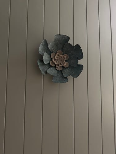 Customer's Flavio green embossed metal flower wall decor mounted on a vertical panel wall.