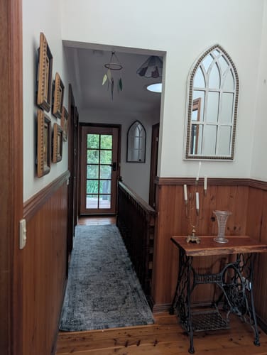 Customer's Gothic Arch Window Mirror mounted on a white wall above a wooden table in a hallway.