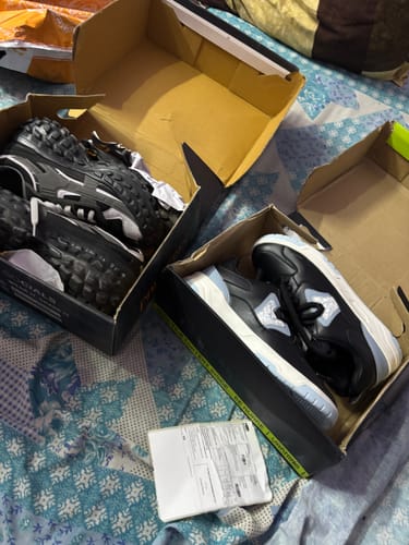 Customer's Stride Eclipse sneakers in black and white, resting inside two open shoeboxes on a patterned surface.
