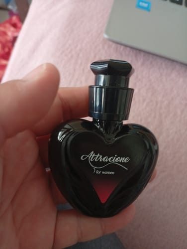 Customer's hand holding a black heart-shaped Attracione perfume bottle.