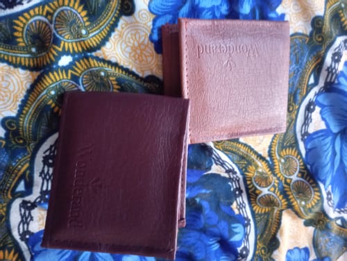 Customer's two brown leather wallets labeled Wonderand placed on a colorful patterned fabric surface.