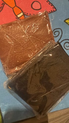 Customer's two wrapped wallets, one brown and one black, received instead of the Spiderman wallet