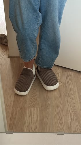 Customer's HappyCozy slippers worn on feet, showing the brown corduroy fabric and white sole.