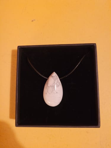Customer's Collier Howlite pendant, shaped like a white and grey drop, displayed in a black gift box.