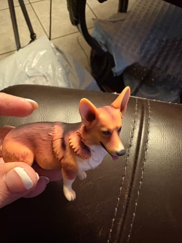 Customer's custom 3D dog figurine, showing brown and black markings, being held by a hand.