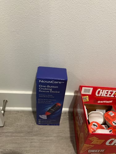 Customer's NovaCare choking rescue device box sitting on a pantry floor next to a box of Cheez-Its.