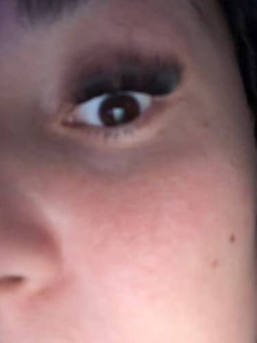 Kundenfoto der Wimpern Glow On, Nahaufnahme eines Auges mit applizierten, dunklen Wimpernextensions.