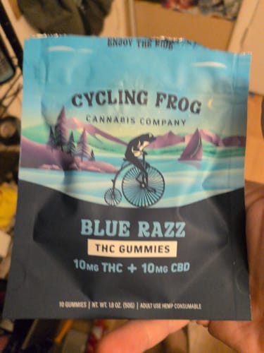 Customer's hand holding a blue, illustrated pouch of Cycling Frog Blue Razz THC Gummies.