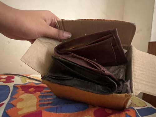 Customer's cardboard box containing a brown and black wallet that the reviewer claims is not the Spiderman wallet