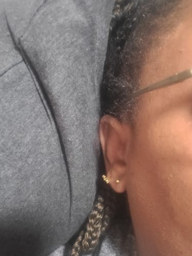 Customer's gold Comfort Earrings worn on earlobe, close-up shot showing earring placement.