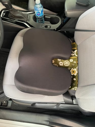 Customer's black Rab memory foam tailbone cushion placed on a grey car seat.
