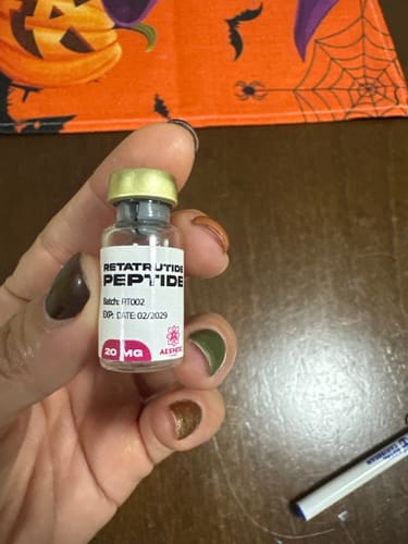 Customer's hand holding a small Aesthetic RX20 Retatrutide peptide vial with a golden cap.