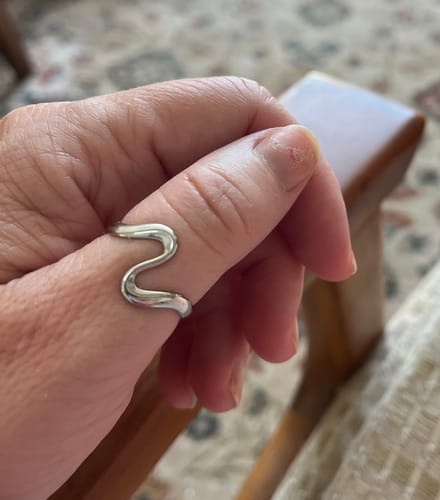 Customer's Silver Wave Ring worn on their thumb, showing the simple wave design.