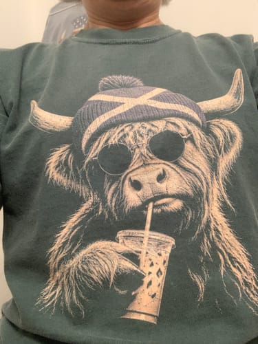 Customer's forest green Highland Cow Beanie Long Sleeve Shirt, featuring a graphic of a cow wearing a beanie and sunglasses.