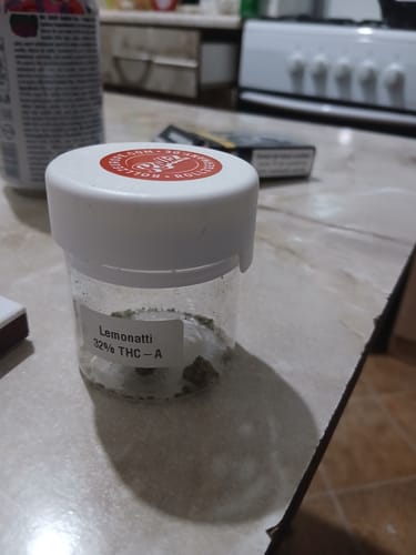 Customer's Lemonatti THC-A flower container with a white cap sitting on a kitchen counter.
