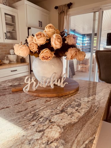 Customer's Faux Large Rose Arrangement in a beige vase on a kitchen counter with a Grateful sign.