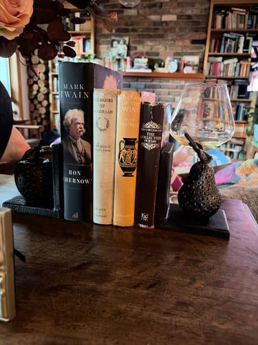 Customer's Poire French Provincial Pear and Apple bookends holding a row of books on a wooden shelf.