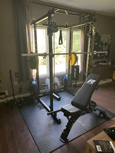 Customer's RitFit P3 Power Cage home gym set up on floor mat with weight bench and weight plates installed.
