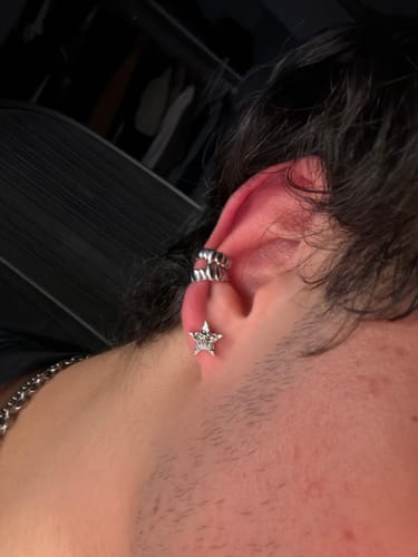 Customer's silver ear cuffs worn on their ear, paired with a star earring.