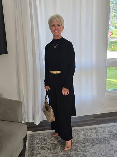Reviewer wearing a black Petite Essential Set styled with a gold belt and necklace.