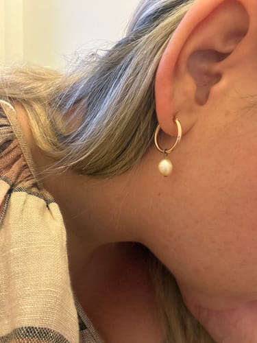 Reviewer wearing a 9ct Rose Gold rounded hoop earring with a small pearl charm attached.