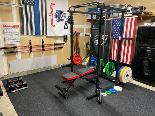 Customer's RitFit PPC03 Power Cage with attached bench and weight plates in a home gym setting.