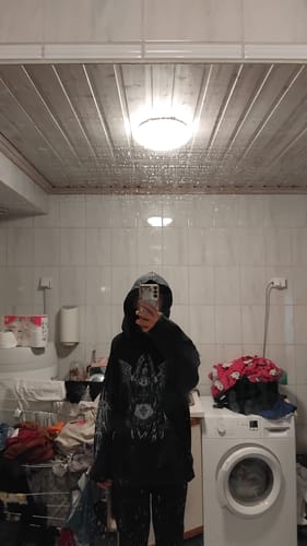 Customer's mirror selfie wearing the black oversized Hoodie Ange with a large white winged angel graphic.