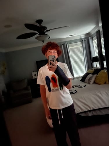 Customer's white Ycoa t-shirt with a multi-colored thermal print, worn in a bedroom mirror selfie.