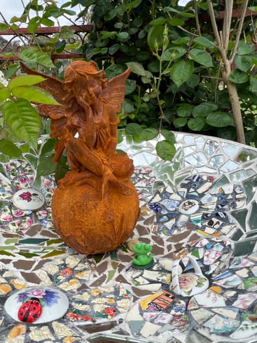 Customer's rust-colored Lady Ophelia French Provincial fairy statue, perched on a mosaic tile surface outdoors.