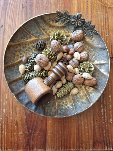 Customer's Alida French Provincial Leaf Dish in antique gold, filled with pinecones, nuts, and a wooden nutcracker.
