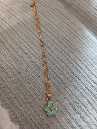 Customer's Turquoise Sakura Bloom Gold Necklace featuring a light blue flower pendant on a dainty gold chain.