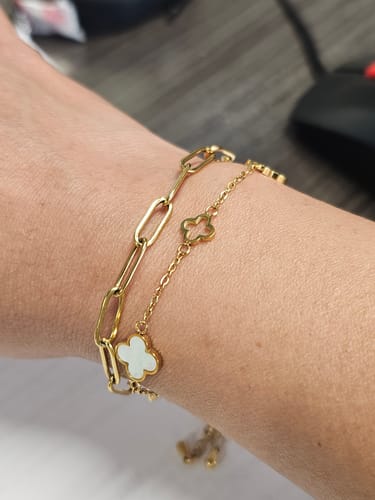 Customer's Lucia Clover Bracelet worn on wrist, showing gold chain with white clover accents next to a linked chain