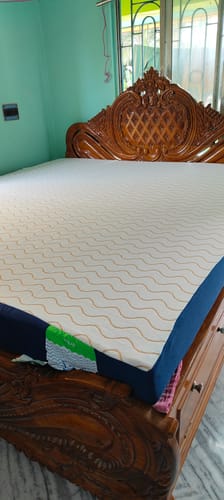 Customer's Flo Aloe Vera Gel Infused Waterproof Mattress Protector fitted neatly on a large, ornate wooden bed frame.