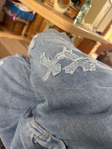 Customer's Jean Bleu Croix showing the distressed light blue denim with textured cross motifs on the leg.