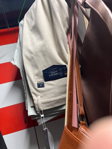 Customer's cream textured corduroy pants with product tag hanging on a rack.